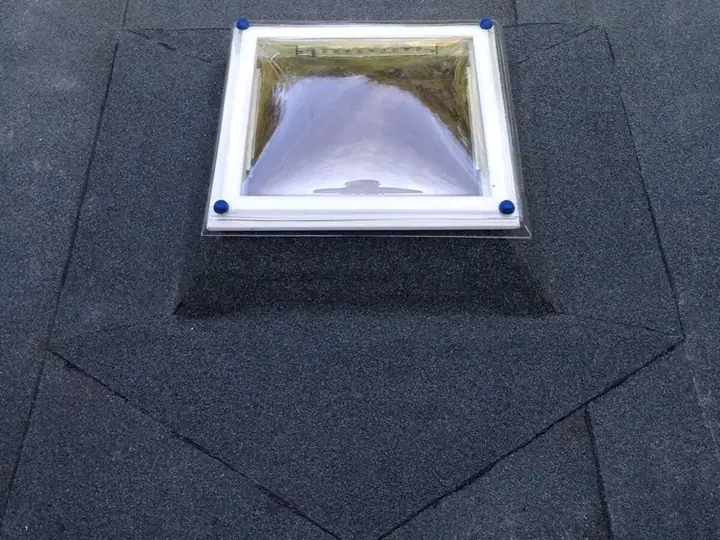 Nieuwe lichtkoepel op een plat dak, de dakbedekking is in een keurige kraag om het kader opgewerkt